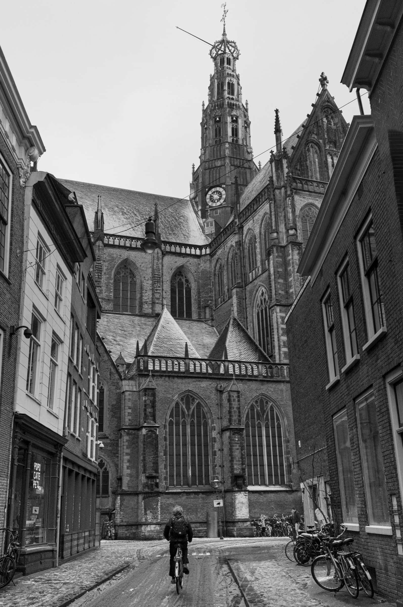 Saint Bavo — De Grote of St.-Bavokerk boven een besneeuwde straat in het hart van Haarlem. Een eenzame fietser passeert onder de torenspits die de stad al vijf eeuwen draagt.